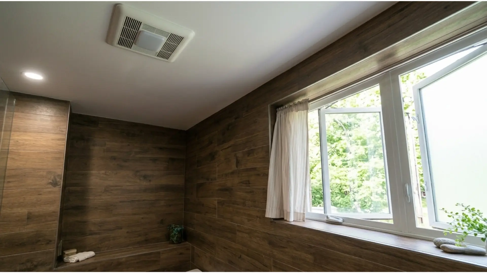 Bathroom ventilation fan and large window with wood accents